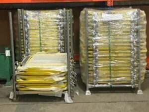Warehouse storage of yellow powder-coated scaffold ladder gates / swing safety gates, complete with mesh infill, integrated toe boards, and attachment clamps, ideal for tube-and-fitting or system scaffolding safety compliance
