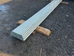 Bundle of new galvanised steel scaffold tubes stacked in a yard