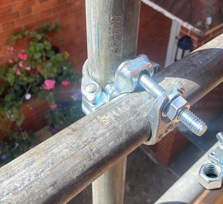 Close-up of scaffold tubes and fittings showing forged couplers and galvanised finish