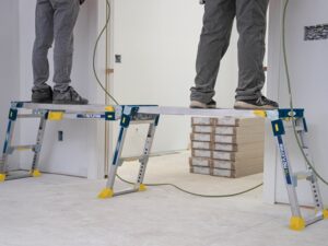 Two tradespeople using an adjustable linking PRO work platform connected across a work area for stable elevated access