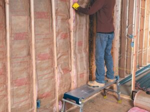 Compact PRO Work Platform in use by tradesperson installing wall insulation, showing stable wide aluminium platform and non-slip surface
