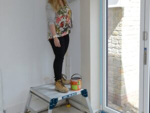 Person using Odd Job 600 work platform for interior painting showing stable large standing surface