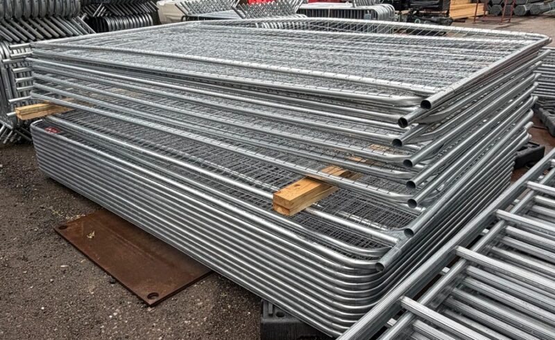 Galvanised Heras temporary fencing panels stacked in the yard